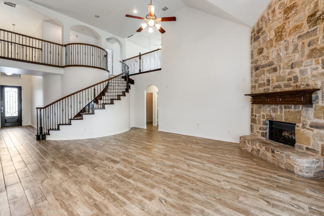 Living room with floor-to-ceiling stone fireplace and refinished hardwood floors