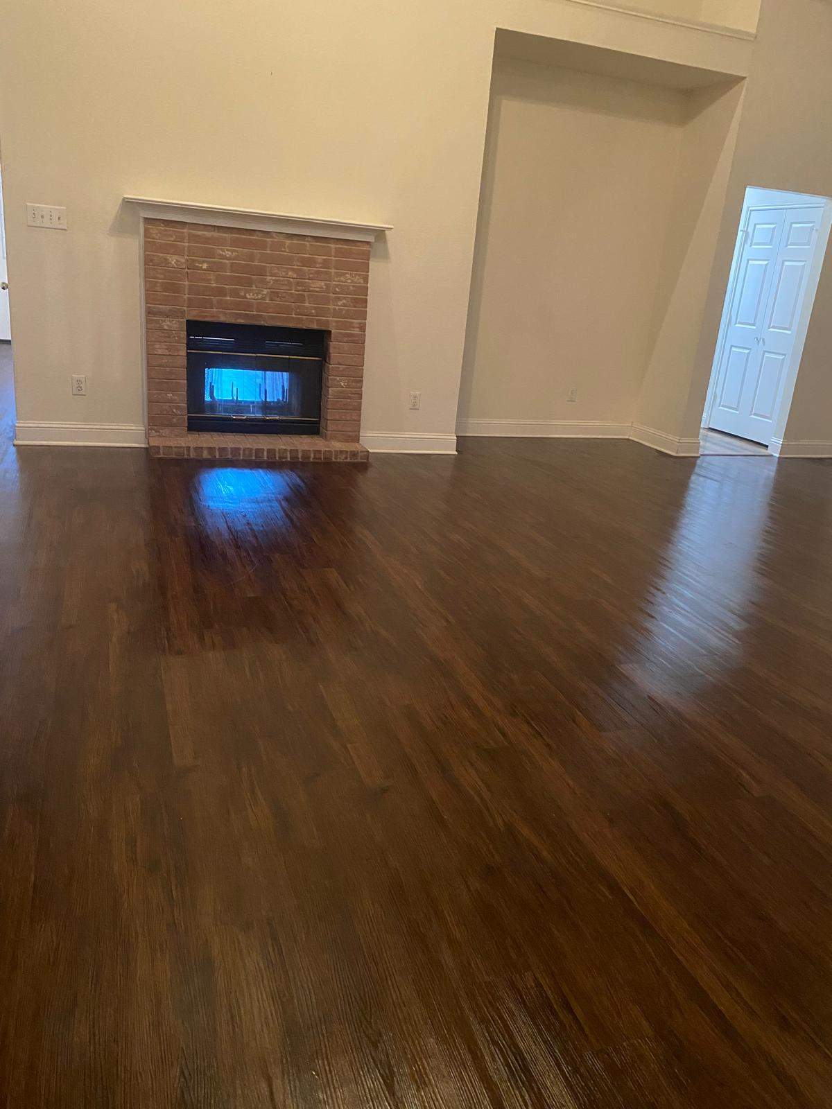 Refinished hardwood floors in living room with brick fireplace